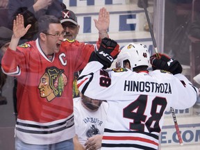 The Blackhawks' Vincent Hinostroza celebrates his goal against the Canucks with a fan.