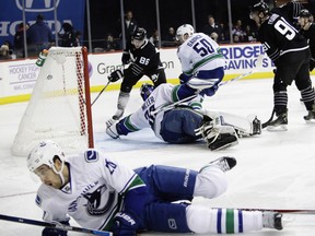 The Islanders' Nikolay Kulemin (86) shoots the puck past Vancouver Canucks goalie Ryan Miller (30) as Brandon Sutter (20) falls down.