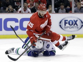 Red Wings defenseman Mike Green (25) falls over Vancouver Canucks defenseman Luca Sbisa (5) after passing the puck during the second period of an NHL hockey game, Thursday, Nov. 10, 2016, in Detroit.