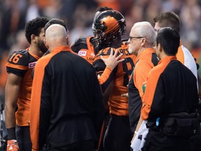 B.C. Lions' Emmanuel Arceneaux, centre, is helped off the field by players and staff after being hit by Winnipeg Blue Bombers' Taylor Loffler.