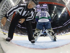 This is what life looks like for the Canucks: linesman Devin Berg fishing the puck out of Ryan Miller's net during the loss against the New York Islanders Monday. Bruce Bennett/Getty Images