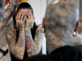 A woman covers her face during the International Tattoo Convention in Bucharest, Romania last month. Having too much ink, especially on the face, can be a drawback in the corporate world.