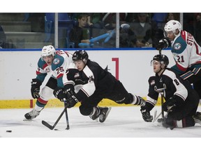 James Malm of the Vancouver Giants lunges for a loose puck in front of the outstretched Cal Foote of the Kelowna Rockets during Friday's Western Hockey League action at the Langley Events Centre. Alec Baer of the Giants and Devante Stephens of the rockets trail the play in the all-B.C. battle.