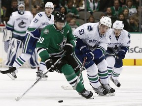 Dallas Stars' Jason Spezza (90) tries to control the puck as Vancouver Canucks' Bo Horvat (53) and Jayson Megna (46) apply pressure during the second period of an NHL hockey game, Friday, Nov. 25, 2016, in Dallas.