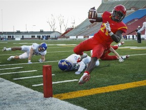 University of British Columbia Thunderbirds look on as University of Calgary Dinos' Jeshrun Antwi scores a touchdown during second half CIS Hardy Cup football action in Calgary, Saturday.