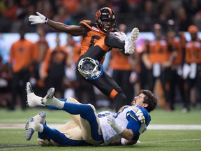 Winnipeg Blue Bombers' Ian Wild, bottom, loses his helmet after colliding with B.C. Lions' Stephen Adekolu, top, and teammate Khalil Bass, back, during first half western semifinal CFL football action.