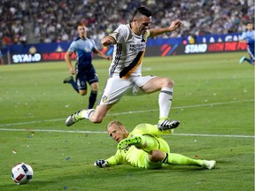 Robbie Keane vaults a challenge by goalkeeper David Ousted during a Galaxy-Whitecaps game in July.Might they be teammates next season?