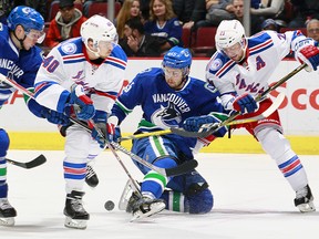 Derek Stepan and Michael Grabner combine to check Michael Chaput of the Canucks.
