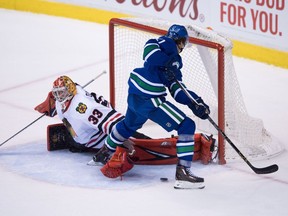 Chicago Blackhawks' goalie Scott Darling, left, loses his glove as he stops Vancouver Canucks' Loui Eriksson during the overtime period of Saturday's game at Rogers Arena.