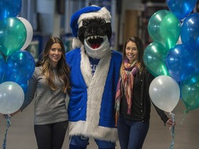 Lauren Sbisa (left) and Giselle Sutter (right) join Fin at Rogers Arena. Canucks wives and girlfriends will be raising money for the Empty Stocking Fund during the team's home game on Thursday.