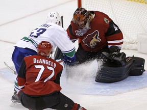 Vancouver Canucks center Bo Horvat (53) scores a goal against Arizona Coyotes goalie Mike Smith, right, as Coyotes defenseman Anthony DeAngelo (77) arrives late to defend during the second period of an NHL hockey game Wednesday, Nov. 23, 2016, in Glendale, Ariz.