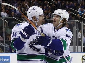 Alexandre Burrows, left, celebrates his third-period goal against the Rangers with Canucks teammate Ben Hutton on Tuesday. Vancouver won 5-3.