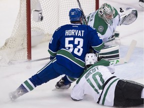 Vancouver Canucks #53 Bo Horvat pushes to the net while pressured by Dallas Stars #10 Shawn Horcoff and goalie Kari Lehtonen in the first period of a regular season NHL hockey game at Rogers Arena, Vancouver, March 28 2015.