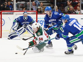 Alex Burrows and Troy Stecher of the Canucks check Erik Haula.