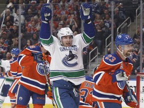 Vancouver Canucks' Alex Burrows (14) celebrates a goal as Edmonton Oilers' Matt Hendricks (23) skates by during third period NHL action in Edmonton, Alta., on Saturday December 31, 2016.