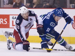 Troy Stecher fights for control of the puck with Boone Jenner.