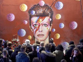 Crowds gather to read and place floral tributes beneath a mural of British singer David Bowie, painted by Australian street artist James Cochran, aka Jimmy C, following the announcement of Bowie's death, in Brixton, south London, on January 11, 2016. NIKLAS HALLE'N / AFP/GETTY IMAGES