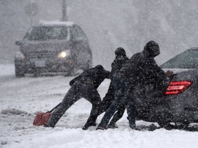 People push a car at Simon Fraser University in Burnaby during the Lower Mainland's first snowfall on Monday. Vancouver drivers are mocked for their winter driving skills, but they face some of the toughest conditions in the country.