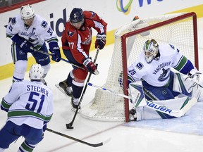 Capitals right wing T.J. Oshie tries to get past Canucks center Henrik Sedin and Troy Stecher.