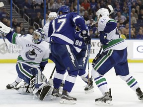 Vancouver Canucks goalie Ryan Miller (30) bats the puck out of the air after making a save on a shot by Tampa Bay Lightning left wing Alex Killorn.