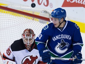 A shot sails over New Jersey Devils' goalie Cory Schneider, left, and Vancouver Canucks' Bo Horvat during the second period of an NHL hockey game in Vancouver, B.C., on Sunday November 22, 2015.