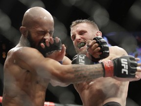 Tim Elliott, right, hits Demetrious Johnson during a mixed martial arts flyweight bout Saturday, Dec. 3, 2016, in Las Vegas.