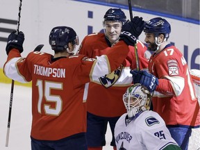 Florida Panthers center Derek MacKenzie (17) celebrates with teammates Florida Panthers right wing Paul Thompson (15) and Florida Panthers center Colton Sceviour (7) after MacKenzie scored against Vancouver Canucks goalie Jacob Markstrom (25) in the second period of an NHL hockey game, Saturday, Dec. 10, 2016, in Sunrise, Fla.