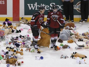 Vancouver Giants Jack Flaman (18) and Johnny Wesley (39) help pick up stuffed animals thrown during the Dec. 18, 2015, Teddy Toss game against the Everett Silvertips.