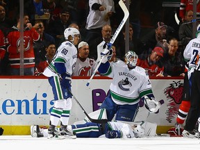 Jacob Markstrom calls for medical attention as teammate Philip Larsen lays on the ice after being injured on a hit by Taylor Hall.