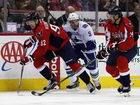 Evgeny Kuznetsov #92 and Justin Williams #14 of the Washington Capitals go after the puck against Troy Stecher #51 of the Vancouver Canucks in the third period at Verizon Center on December 11, 2016 in Washington, DC.