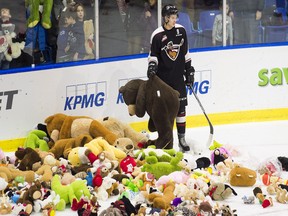 Taden Rattie of the Vancouver Giants picks up a teddy bear that was thrown on the ice during the annual "Teddy Bear Toss" during the first period of their WHL game against the Portland Winterhawks at the Langley Events Centre on December 16, 2016. Teddy bears are thrown onto the ice after the Giants score the first goal of the game to benefit local charities.