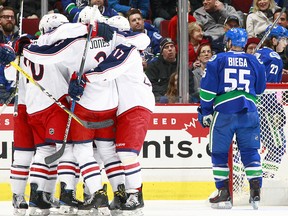 Alex Biega #55 of the Vancouver Canucks skates away as the Columbus Blue Jackets celebrate a goal by Brandon Saad #20 during their NHL game at Rogers Arena December 18, 2016 in Vancouver, British Columbia, Canada.