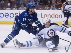 ancouver Canucks defenceman Ben Hutton (27) fights for control of the puck with Winnipeg Jets right wing Patrik Laine (29) during first period NHL action.