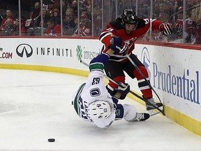 Vancouver Canucks centre Michael Chaput, far left, grabs at New Jersey Devils left-winger Taylor Hall (9) as other players rush up over defenceman Philip Larsen, bottom, who was knocked out by Hall during an NHL game on Dec. 6, 2016, in Newark, N.J. Larsen left the game on a stretcher.