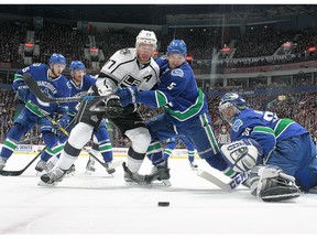 Luca Sbisa checks Jeff Carter in front of Ryan Miller's net.