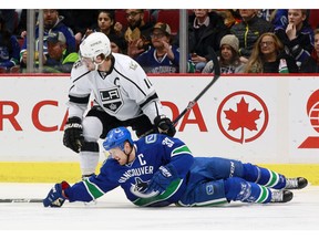 Henrik Sedin reaches for the puck in front of Anze Kopitar.