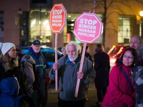 Paul George, centre, holds signs during a protest against the Kinder Morgan Trans Mountain Pipeline expansion in Vancouver on Nov. 29. Prime Minister Justin Trudeau approved the $6.8-billion project that will nearly triple the capacity of the pipeline that carries crude oil from near Edmonton to Burnaby to be loaded on tankers and shipped overseas.