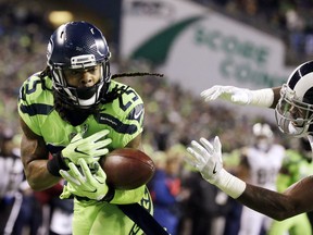 Seattle Seahawks cornerback Richard Sherman, left, bobbles a pass intended for Los Angeles Rams wide receiver Kenny Britt, right, in the first half of an NFL football game, Thursday, Dec. 15, 2016, in Seattle.