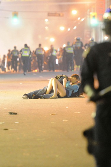Scott Jones and Alexandra Thomas have a moment on the street while police try to disperse a rioting crowd following Game 7 of the 2011 Stanley Cup final in Vancouver.