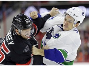 Vancouver Canucks' Luca Sbisa (5), of Italy, and Carolina Hurricanes' Ron Hainsey (65) fight during the first period of an NHL hockey game in Raleigh, N.C., Tuesday, Dec. 13, 2016.