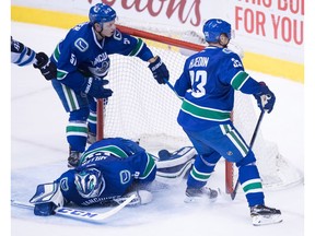 Troy Stecher, Ryan Miller and Henrik Sedin react after a Jets goal.