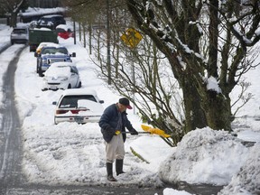 A man attempts to shovel snow in front of his house on Brock street near Nanaimo in east Vancouver.
