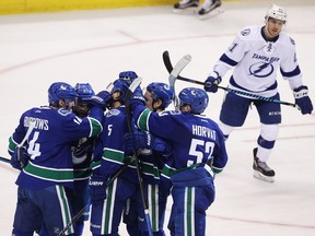 Vancouver Canucks' Luca Sbisa (5) celebrates his goal against the Tampa Bay Lightning with teammates Alexandre Burrows (14), left, and Bo Horvat (53) during second period NHL hockey action in Vancouver on Friday, December 16, 2016.