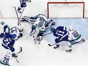 Brayden Point and Brian Boyle look for the puck against Ryan Miller.