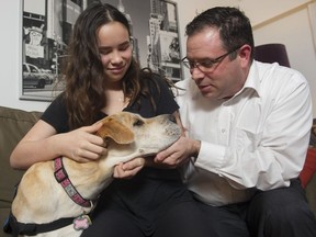 Jayna Lunny, 13, and her dad James hold his service dog Chevy. Jayna wants to donate $1,000 so that another RCMP officer's family can adopt a service dog.