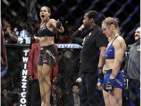 Amanda Nunes, left, celebrates her win as Ronda Rousey stands at right, after their women's bantamweight championship mixed martial arts bout was stopped in the first round at UFC 207, Friday, Dec. 30, 2016, in Las Vegas.