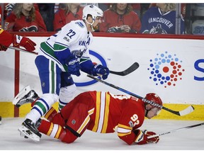 Canucks winger Daniel Sedin knocks over Flames forward Sam Bennett during Vancouver's 3-1 loss in Calgary on Saturday. Sedin says the Canucks need to just try and play their home game on the road.