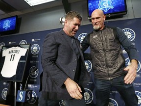 Seattle Mariners former designated hitter Edgar Martinez, left, is greeted by former teammate Jay Buhner following a news conference announcing the retirement by the team of Martinez's jersey No. 11, on Tuesday, Jan. 24, 2017, in Seattle. The Mariners will retire Martinez's number as he continues to move closer to induction in the baseball Hall of Fame. Team president Kevin Mather said that Martinez's number will be officially retired Aug. 12 as part of a weekend celebration.