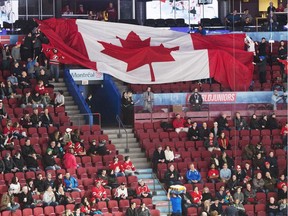 Empty seats are seen as fans pass around a giant Canadian flag before Monday's world junior hockey championship game between Czech Republic and Canada in Montreal.