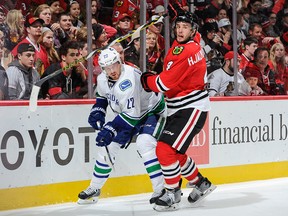 Daniel Sedin and Niklas Hjalmarsson get physical during the NHL game at the United Center on December 13, 2015 in Chicago, Illinois.
